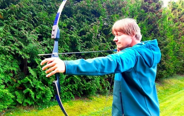 Archery | Team activity | FoRestful - A participant aiming a bow at a target.
