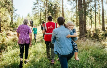 Elämyksellinen eläinkävely - Helppokulkuinen eläinkävely maaseutumiljöössä Hanhenlennossa Iisalmessa. Kuvassa poro, lapset ja aikuinen kesäisellä kukkaniityllä. 