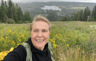 EräKatri Muuramen Riihivuoren huipulla maisemia ihastelemassa. Kukkaketo ja takana alhaalla järvi.