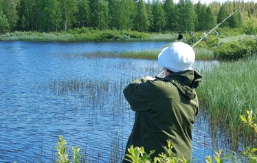 Angler catching a northern pike on a private river expedition in Molkojärvi, Lapland