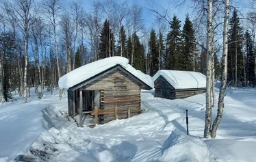 A private wood-fired sauna and an ice fishing hole on a frozen lake in Molkojärvi, Lapland
