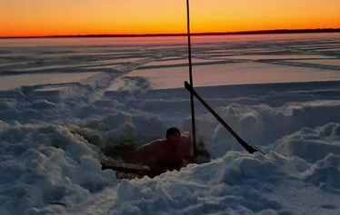 A private wood-fired sauna and an ice fishing hole on a frozen lake in Molkojärvi, Lapland