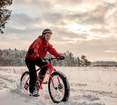 Fatbike-pyöräilyä - Mies fatbike-pyörän kanssa merenrannalla