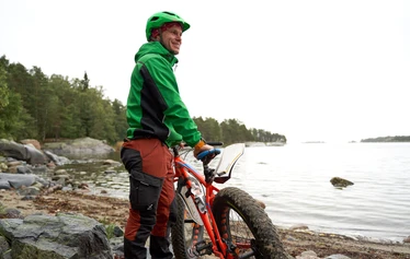 Fatbike-pyöräilyä - Mies fatbike-pyörän kanssa merenrannalla