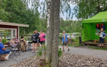 Lettubaarin juhannusjuhla vuodelta 2021 - Harri Kautonen musisoi ja kansa nauttii baarin antimista.