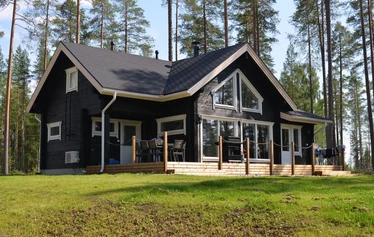 Hiili kuvattuna rannasta päin. - Pohjois-Savossa, Sonkajärven Jyrkän kylällä sijaitsevalla Hiili-loma-asunnolla on iso piha ja terassi, jossa pöytäryhmä 8:lle ja kaasugrilli (kesällä) .