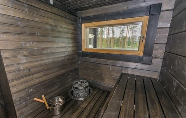 Miilu kuvattuna rannasta päin. - Pohjois-Savossa, Sonkajärven Jyrkän kylällä sijaitsevan Miilu mökin iso terassi, jossa pöytäryhmä 8:lle, kaasugrilli (kesällä) ja  nurmikkoinen takapiha.