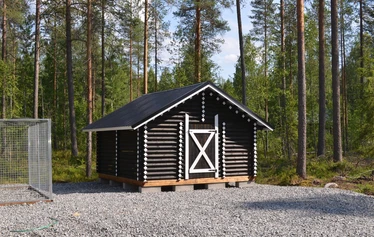 Miilu kuvattuna rannasta päin. - Pohjois-Savossa, Sonkajärven Jyrkän kylällä sijaitsevan Miilu mökin iso terassi, jossa pöytäryhmä 8:lle, kaasugrilli (kesällä) ja  nurmikkoinen takapiha.